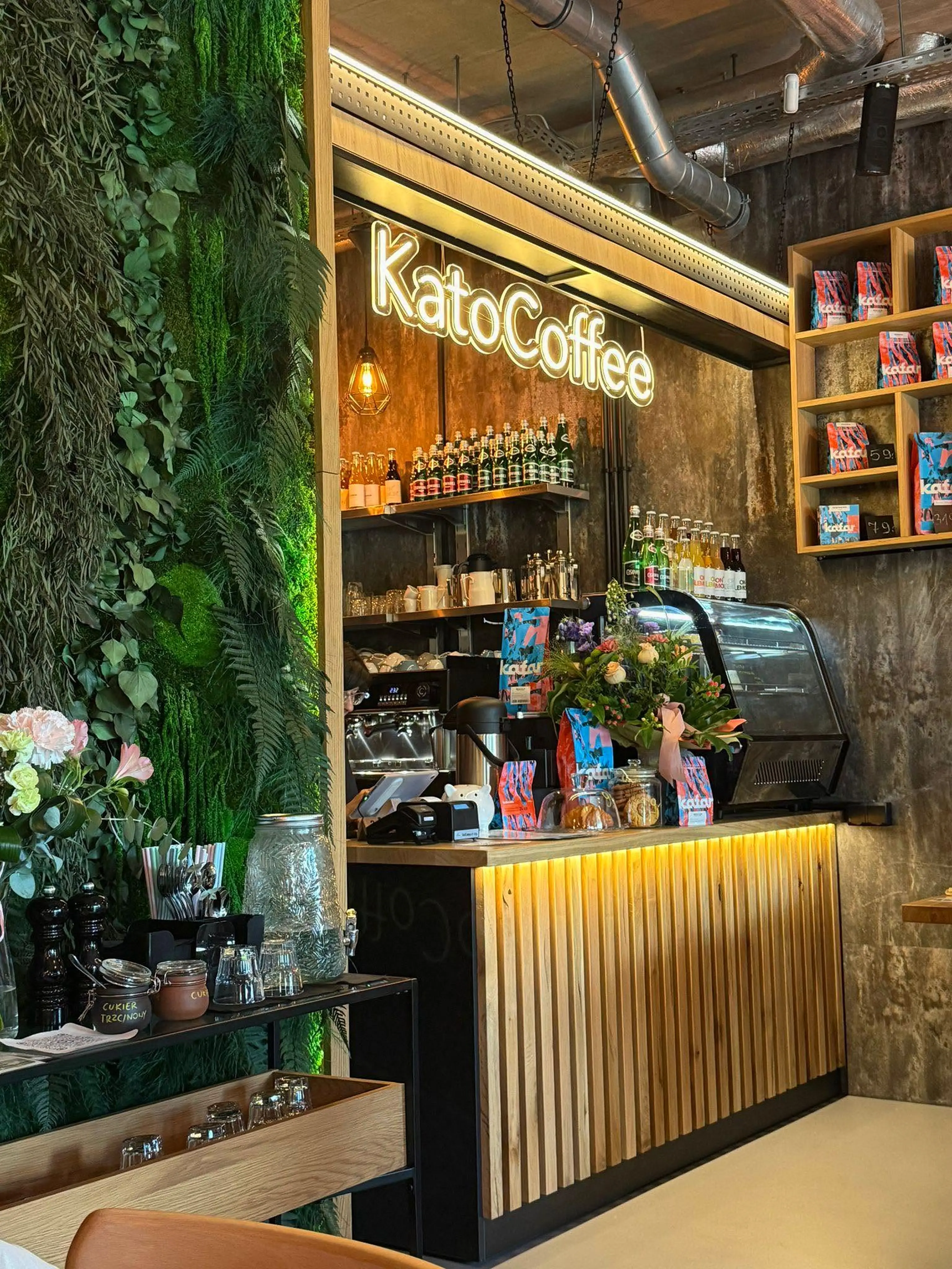 Zielona ściana z mchu i drewniany bar we wnętrzu KatoCoffee